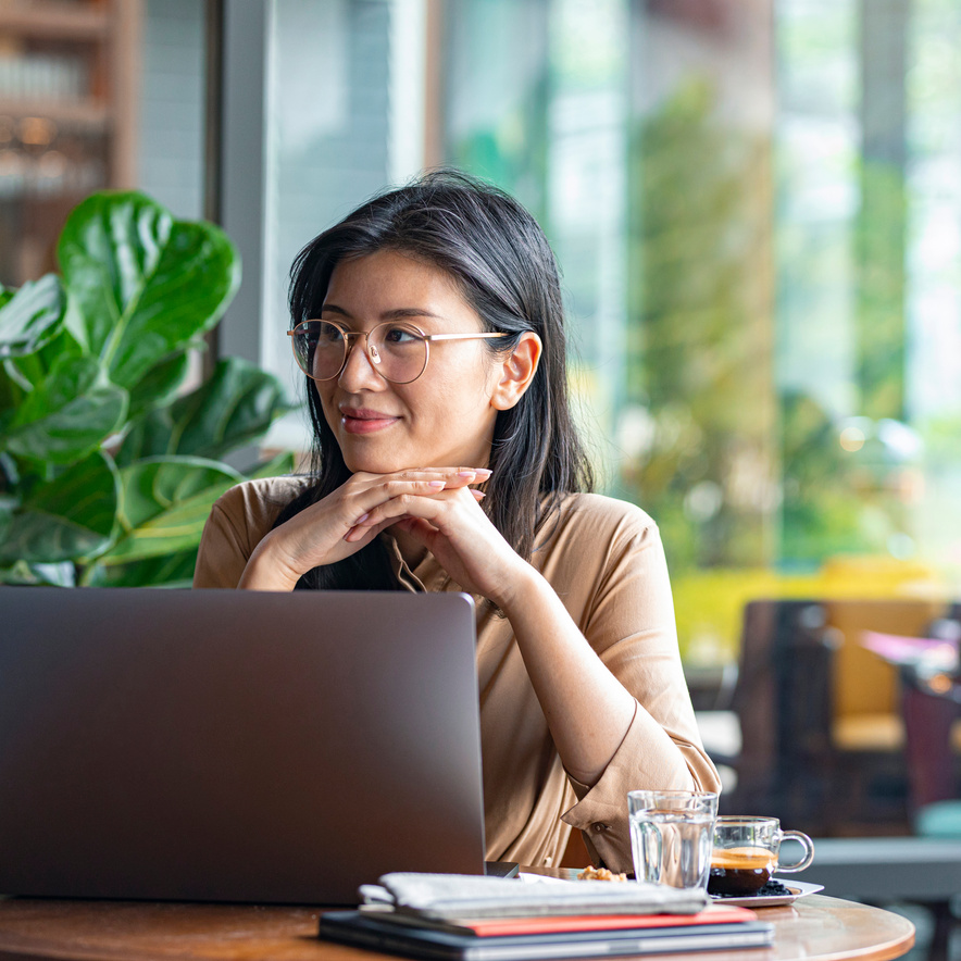 Digital Nomads: Smiling Asian Businesswoman Sitting at a Cafe and Working on Her Laptop Computer